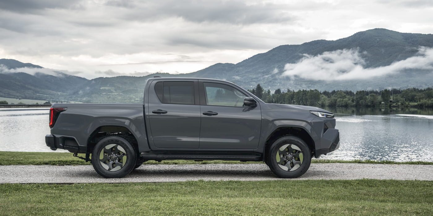 Toyota Hilux BEV в профиль на фоне озера и гор